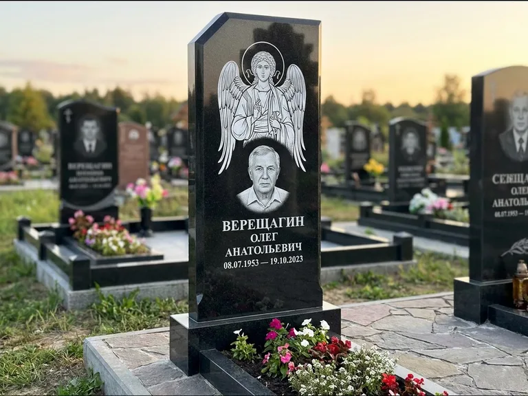 Памятник с гравировкой иконы: стела с резным навершием и нимбом в золоте — гравировка образа Спасителя, высокие разросшиеся туи полукругом, работа «Мельникова» в Пензе