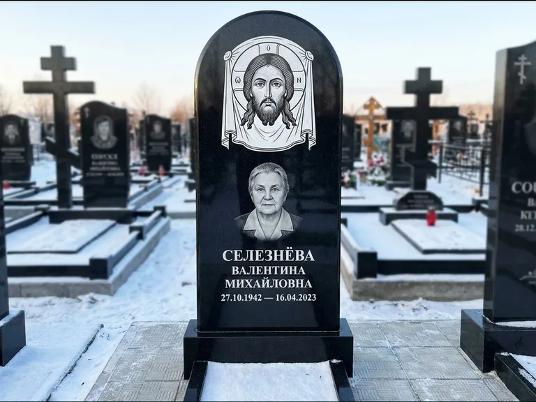 Памятник с гравировкой иконы: небольшая скромная одиночная стела с именной иконой — золочёный нимб на образе, аккуратный участок с газоном, работа «Ковалёв» в Пензе