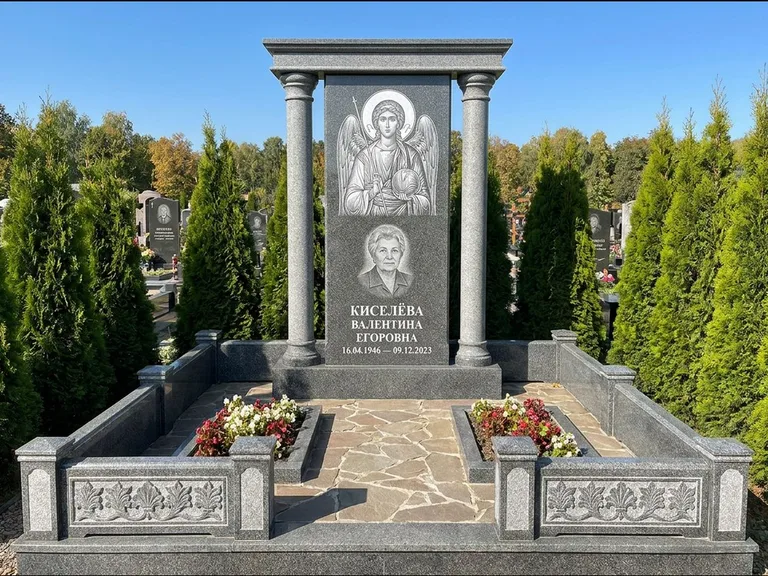 Памятник с гравировкой иконы: массивная стела с двускатным навершием-домиком — гравировка Николая Чудотворца, живая изгородь из туи, работа «Журавлёв» в Пензе