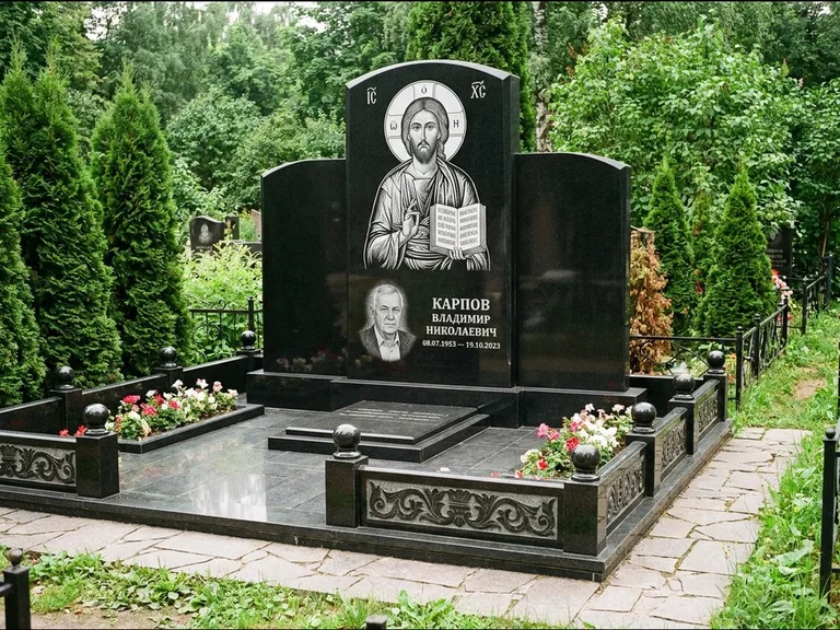 Памятник с гравировкой иконы: широкая панорамная стела с золочёным нимбом — гравировка образа Матроны Московской, цветник с белыми хризантемами, работа «Мельникова» в Пензе