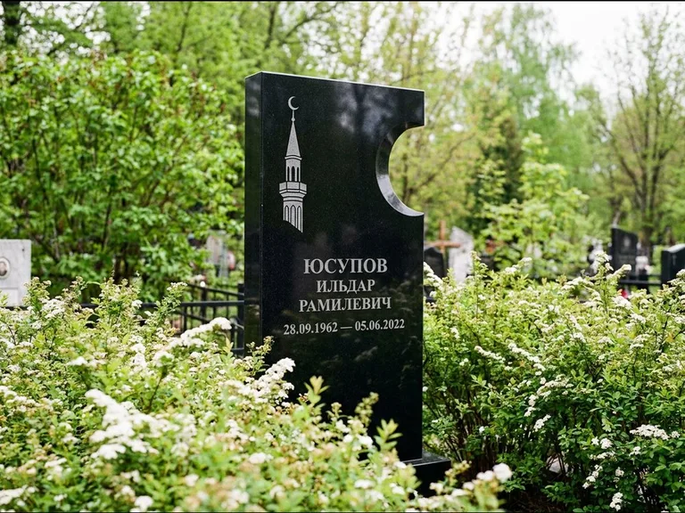 Мусульманский памятник с гравировкой мечети: стела с боковым вырезом в форме полумесяца — гравировка минарета с полумесяцем, низкие кусты спиреи в цвету, работа «Юсупов» в Пензе
